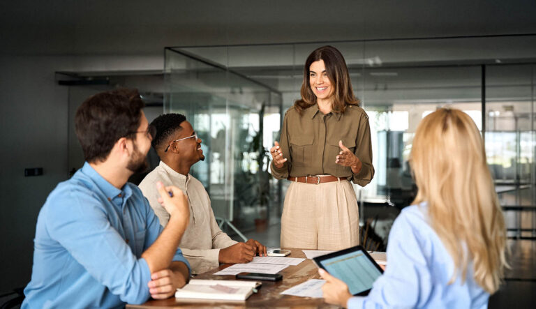 Woman leader standing and talking to her diverse team.